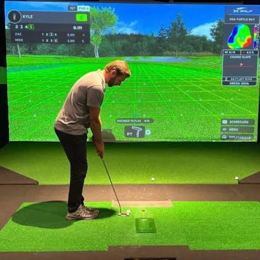 A player putting on turf in front of a full-width golf simulator screen