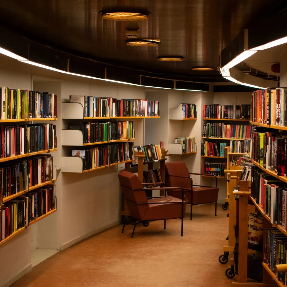 A curved library room lined with bookshelves and two leather reading chairs