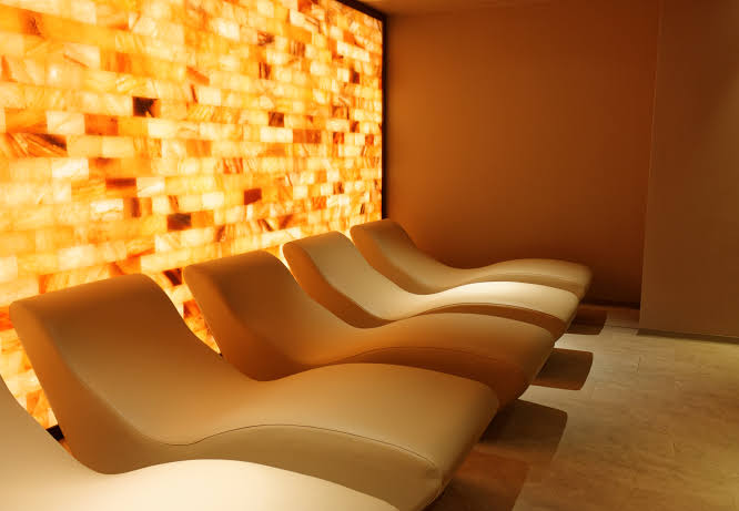 Contoured loungers in front of a backlit Himalayan salt brick wall