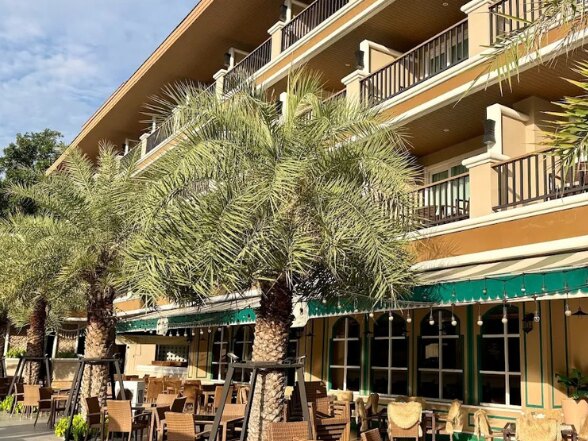 The residence exterior, palm trees over a shaded dining terrace
