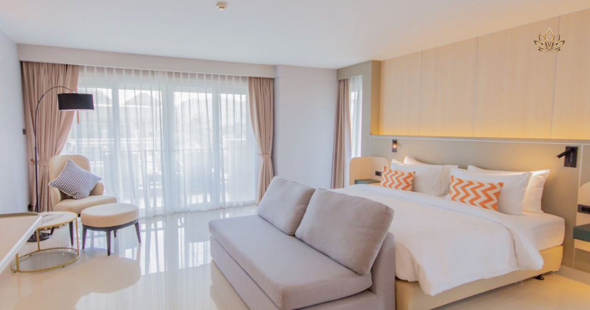 A bright corner suite with a sofa, twin beds and full-height drapes onto the balcony