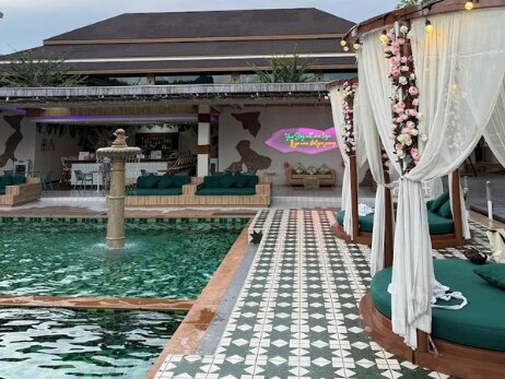 The residence pool with a fountain, tiled deck and curtained daybeds
